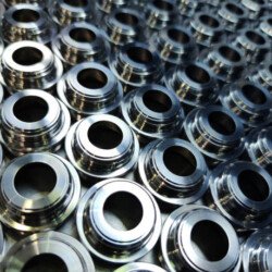 Shiny silver color stainless steel parts background. Regular industrial metal production pattern with selective focus and background blur.